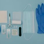 Flat lay of essential first aid items including gloves, mask, and scissors on a light background.